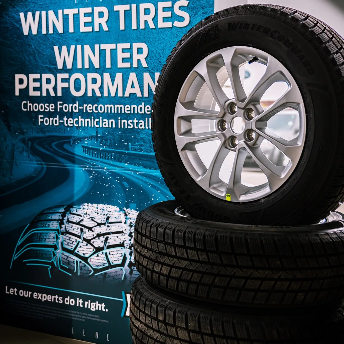 Stacked name-brand winter tires on alloy wheels at Quick Lane Grande Prairie